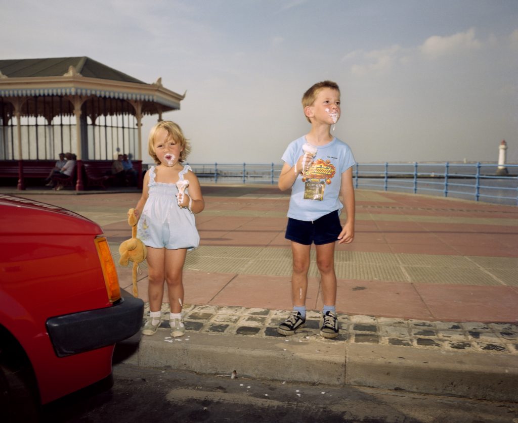 Due bambini ritratti da Parr mentre mangiano un gelato in piedi.